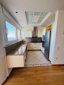 a kitchen with white cabinets and a large window at Viva B&B in Anavyssos