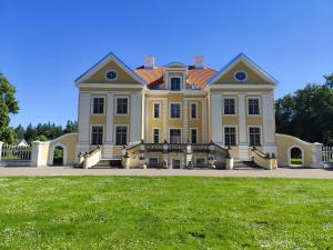 a large yellow house with a grass field in front at Miami Jungle Glamping Experience in Korjuse
