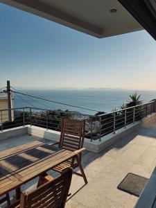 a balcony with a wooden table and chairs and the ocean at Viva B&B in Anavyssos