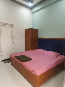 a bedroom with a large bed with pink sheets at Vijay Villa in Faizābād