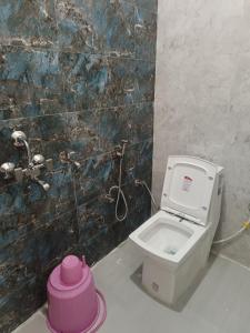 a bathroom with a toilet with a pink pot at Vijay Villa in Faizābād