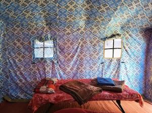 a room with a wall with a bed and two windows at Jungle Valley Camp & Resort in Nainital +22 photos
