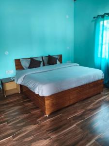 a bed in a room with blue walls and wooden floors at Jungle Valley Camp & Resort in Nainital
