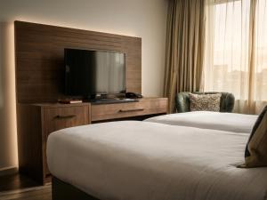 a hotel room with two beds and a flat screen tv at A-Hotel Oosterhout in Oosterhout