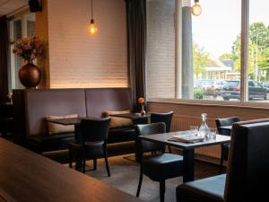 a restaurant with tables and chairs and a window at A-Hotel Oosterhout in Oosterhout