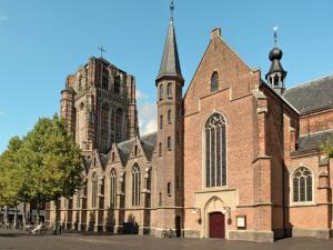 a large brick building with a tower and a church at A-Hotel Oosterhout in Oosterhout +9 photos