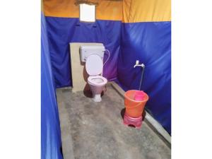 a small bathroom with a toilet in a tent at Jungle Valley Camp & Resort in Nainital