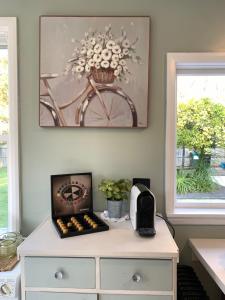 a white dresser with a clock and a bike picture at Cooper's Cottage in Nelson