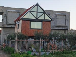 a house with a roof on the side of a building at MiNi chalet en bois in Menzel Abderhaman