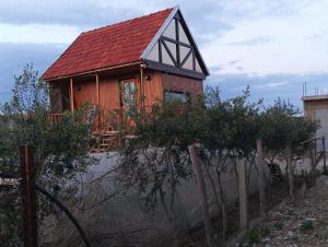 a house with a red roof on top of a fence at MiNi chalet en bois in Menzel Abderhaman +6 photos
