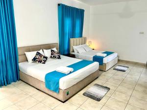 two beds in a room with blue curtains at Hotel One Sixty in Dehiwala
