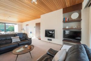 a living room with a leather couch and a fireplace at Zenzalea Oostkamp in Oostkamp