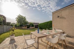 a patio with a wooden table and white chairs at Zenzalea Oostkamp in Oostkamp