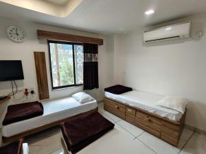 a bedroom with two beds and a window at Hotel Milan in Ahmedabad +54 photos