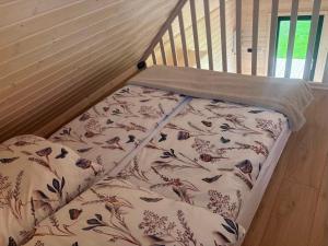 a bed with a blanket and pillows in a crib at PAKLADA Domek całoroczny 2 in Bak