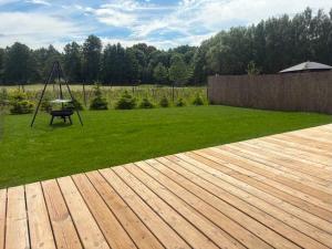 a yard with a wooden deck with a swing at PAKLADA Domek całoroczny 2 in Bak