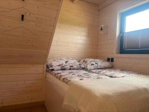 a small room with a bed in a wooden wall at PAKLADA Domek całoroczny 2 in Bak +2 photos