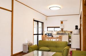 a living room with a green couch and a kitchen at Komorebi/こもれび in Takayama