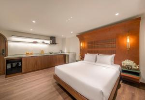 a bedroom with a large white bed and a kitchen at Vista Del Sol Hotel in Danang