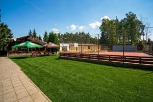 a tennis court with a fence and green grass at Relaxační centrum Orion in Roudná