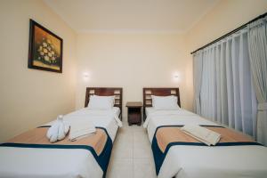 a hotel room with two beds and a window at New Puri Asih Hotel in Kuta +31 photos