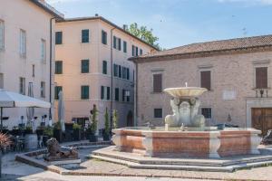 a fountain in the middle of a courtyard with buildings at Effealatapartments - Appartamento del Duca in Senigallia