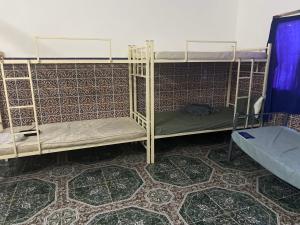 a room with three bunk beds and a tile floor at Beach hostel in Muscat