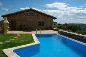 a house with a blue swimming pool in front of a house at Cal Miger in Gualter