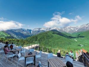 a group of people sitting at tables on a deck with mountains at Restaurant & Hotel Traumerei in Hakuba