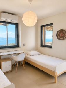 a bedroom with two beds and a desk and windows at Óros Residence - Pool & Panoramic Views in Tzíkidhes
