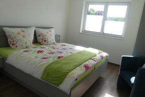 a bed with a green blanket and two windows at Ferienwohnung Wolkenfeld in Kaisersesch +5 photos