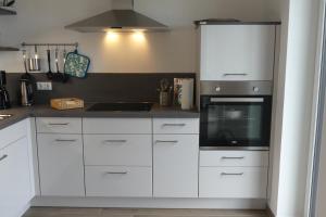 a kitchen with white cabinets and a stove top oven at Ferienwohnung Wolkenfeld in Kaisersesch