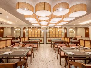 a restaurant with tables and chairs and a large chandelier at Rangalaya Royal in Vellore