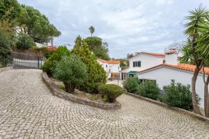a cobblestone driveway with trees and houses at Charming House in Cascais in Alcabideche