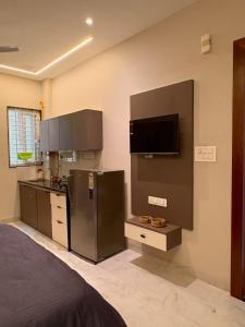 a kitchen with a refrigerator and a tv on the wall at OddbirdStays in Indore