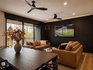 a living room with a table and a tv at Black Sheep alpine getaways in Dinner Plain