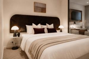 a bedroom with a large white bed with two lamps at Punthill Epping in Epping +64 photos
