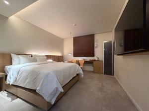a bedroom with a large white bed and a kitchen at SODO Hotel in P'aju