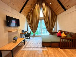 a bedroom with a bed and a desk and a tv at Pahadi Sukoon - A frame Cottages in Dharamshala