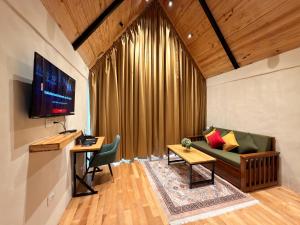 a living room with a couch and a tv at Pahadi Sukoon - A frame Cottages in Dharamshala +23 photos