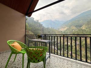 a balcony with two chairs and a table with a view at Pahadi Sukoon - A frame Cottages in Dharamshala