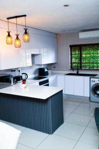 a kitchen with white cabinets and a washer and sink at Riverside 1 bedroom house for Two in Nelspruit