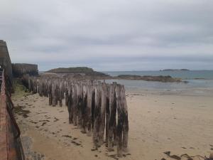 a wooden fence on a beach near the water at Bien être la violette in Saint Malo
