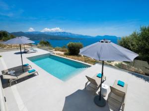 a villa with a swimming pool and an umbrella at Eleage Villas in Lefkada
