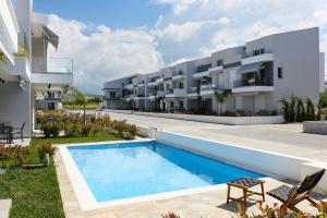 a swimming pool in front of a building at Green Almond Residential Complex in Orfánion