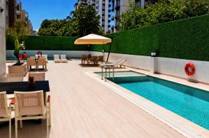 a swimming pool with tables and chairs and an umbrella at Alpek Hotel Antalya - Lara in Antalya