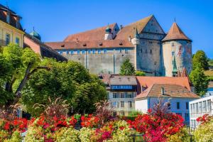 a city with a castle and flowers in the foreground at Appartement de vacances Papillon Stilvoll wohnen im Herzen der historischen Altstadt von Porrentruy in Porrentruy