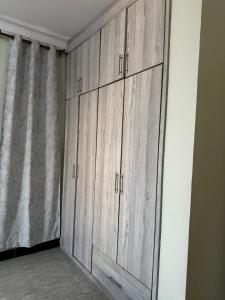 a row of wooden cabinets in a room with a curtain at El SALI APPARENT,Najjera in Namugongo
