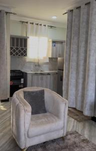 a living room with a chair and a kitchen at El SALI APPARENT,Najjera in Namugongo