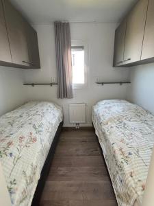 two beds in a small room with a window at Chalet Wad'n Droom in Westerland